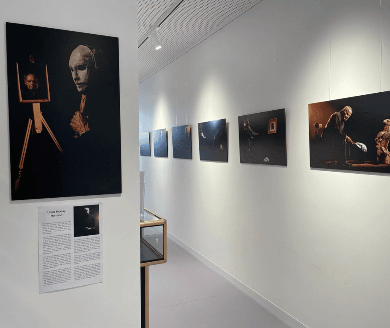 Photos hang on the Ballarat Libraries walls. they are dark coloured photos and feature an elderly Aboriginal elder.